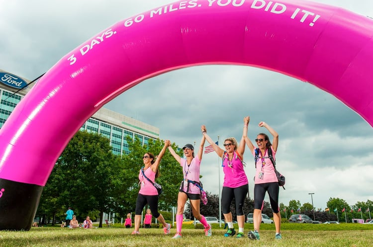 AVON pink inflatable arch with participants at a fundraiser crossing it