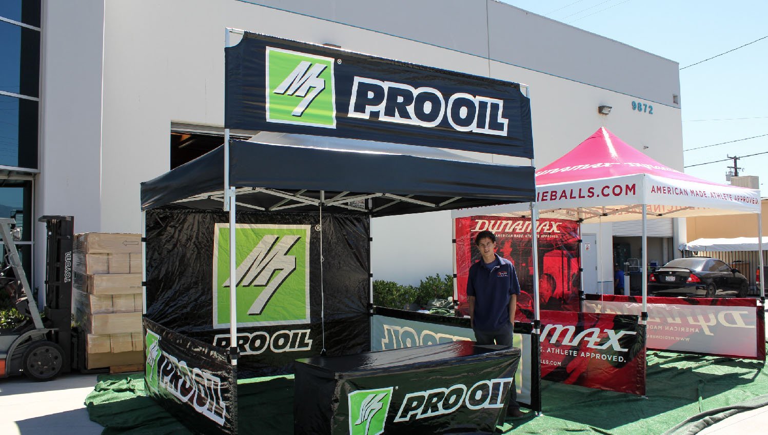Custom canopy display with Pro Oil branding, printed walls, table cover, and overhead sky banner