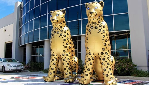 two golden inflatable cheetahs in front of the promotional design group building