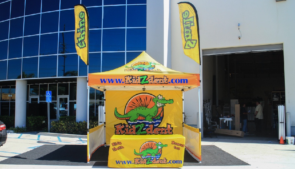 Ad flag canopy package with printed advertising flags, custom tent top, printed back wall, short side walls, and table cover