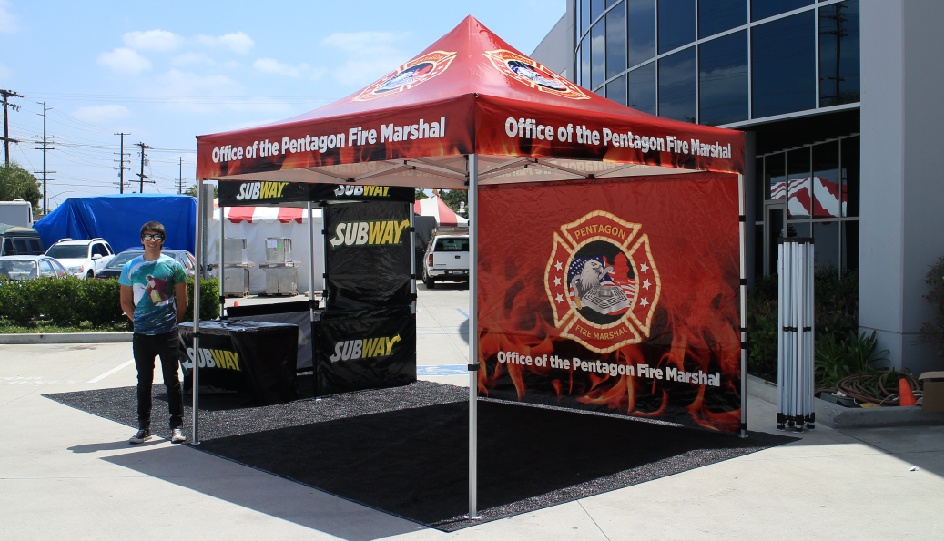 Silver 10x10 canopy package with printed tent top and back wall with subway tent in the background and a printed subway table cover