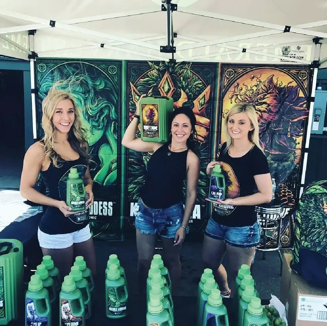 Emerald Harvest trade show booth under a pop up canopy with staff holding nutrient bottles and product lineup on a table. Emerald Harvest trade show booth under a pop up canopy with staff holding nutrient bottles and product lineup on a table.