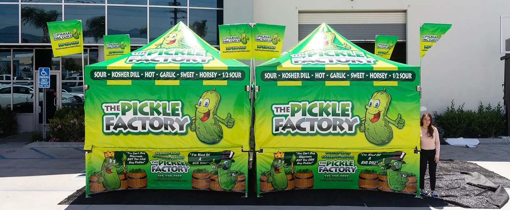 Front view of The Pickle Factory branded pop up canopy booth with printed walls and flags Front view of The Pickle Factory branded pop up canopy booth with printed walls and flags