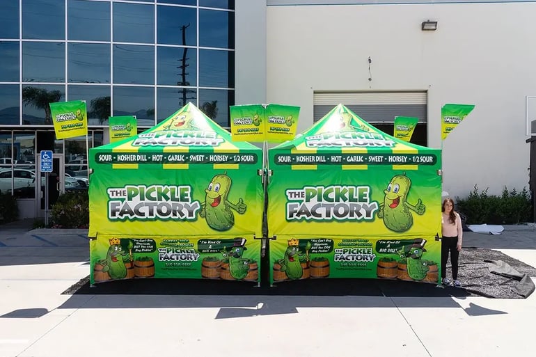 Double pop up canopy booth for The Pickle Factory with full printed walls and tall corner flags