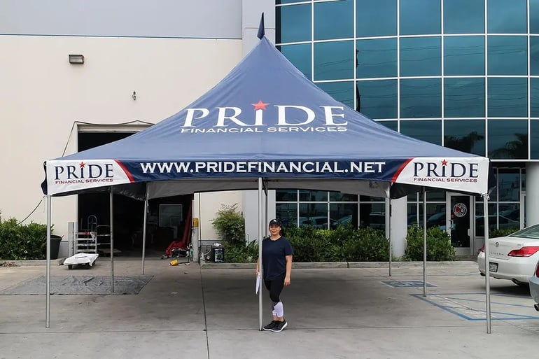High peak event tent with Pride Financial Services branding and website valance shown with person for scale