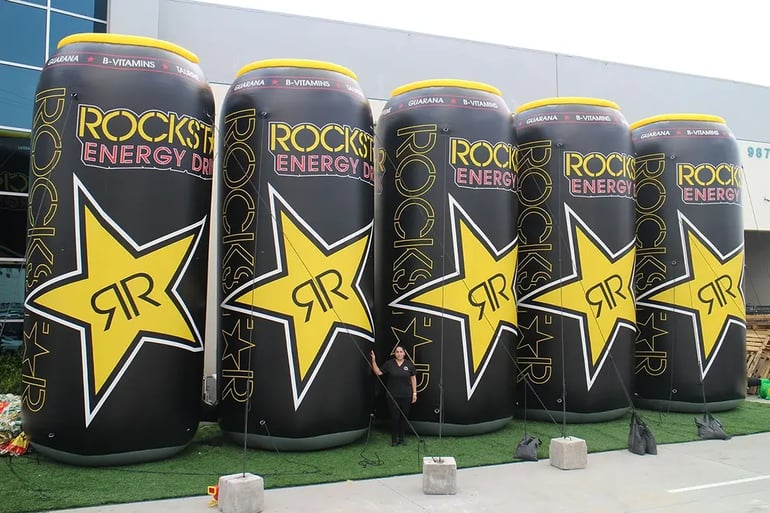  Giant inflatable can replicas shown with a person for scale for branded outdoor event marketing