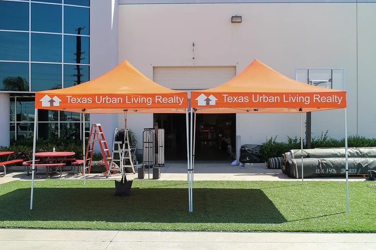 Two branded pop up canopies with Texas Urban Living Realty valance printing for outdoor events