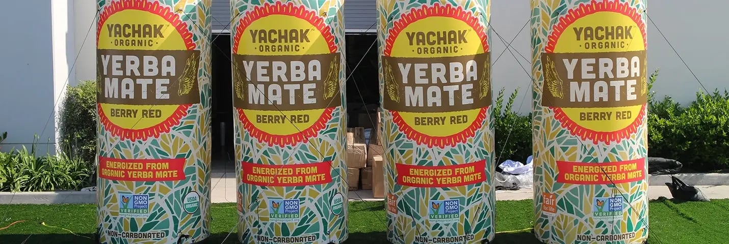 Lineup of giant inflatable can replicas with Yachak Yerba Mate Berry Red graphics for event displays