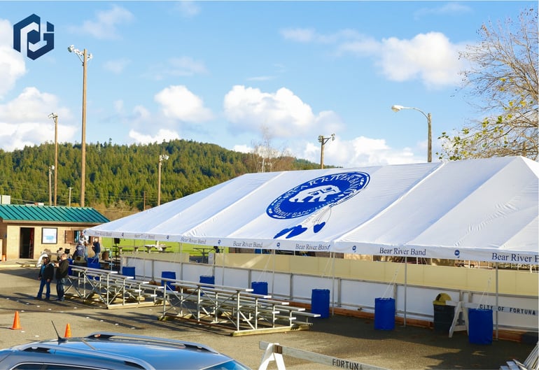 Large event tent with Bear River Band roof logo and covered bleacher seating for outdoor venue use