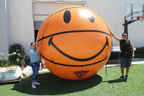 Giant inflatable basketball with smiley face graphics used as a branded event display for Chinatown Market