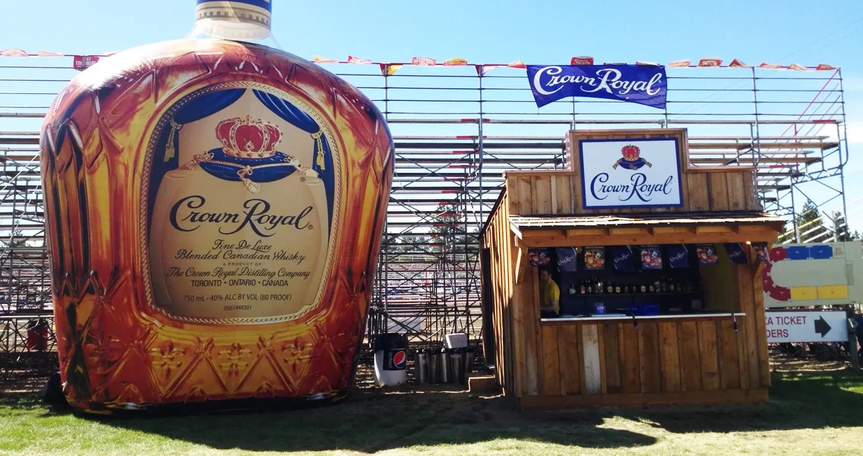 Giant inflatable bottle replica used as a branded event display beside a sampling booth