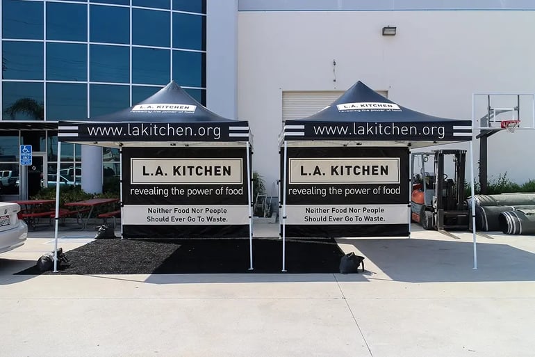 Front view of two branded 10x10 canopy tents with printed back walls and valance text