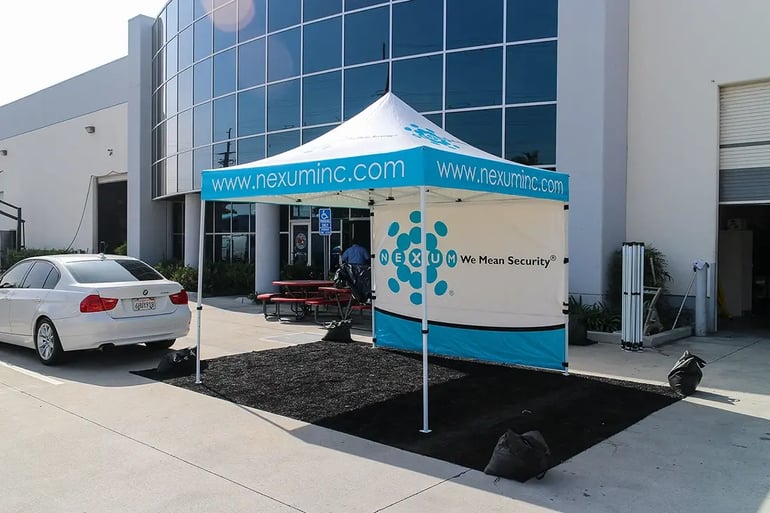 Custom printed pop up canopy with Nexum Inc branding, website valance, and full back wall panel