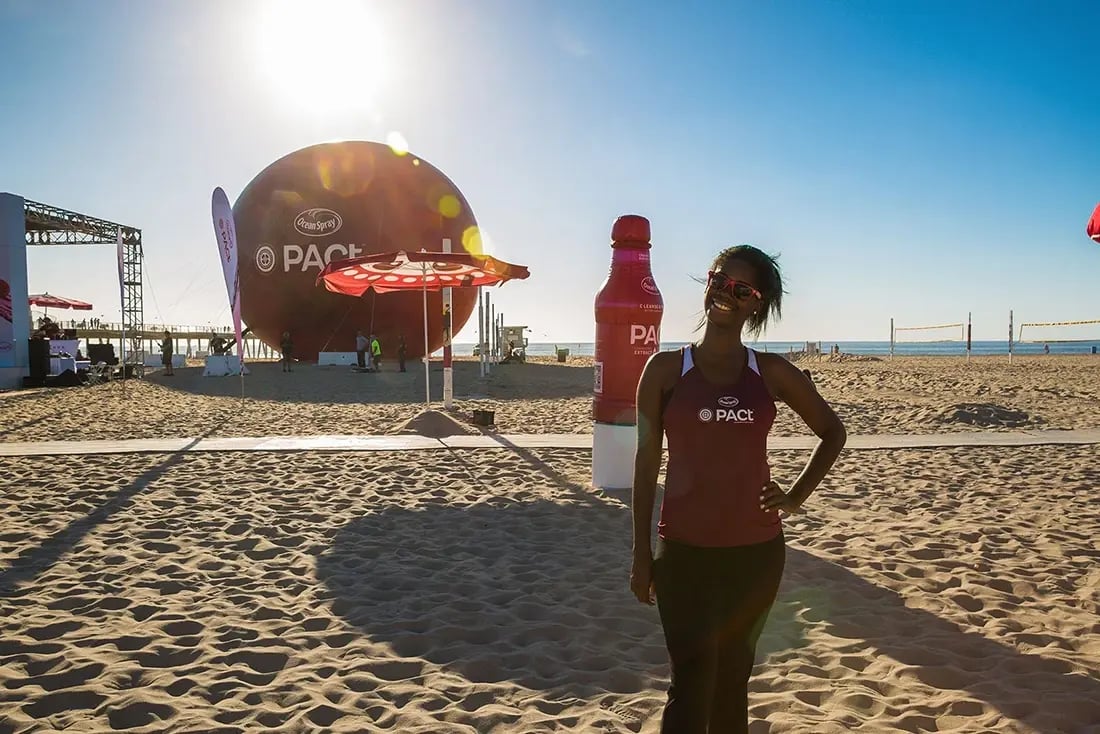 Giant inflatable sphere and bottle used for a beach brand activation with staff and event setup