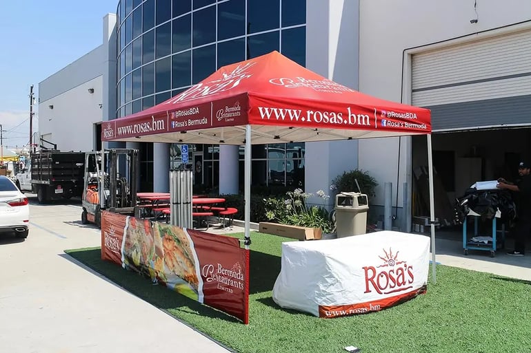 Branded pop up canopy with Rosa’s Bermuda website valance, printed banner, and matching table cover