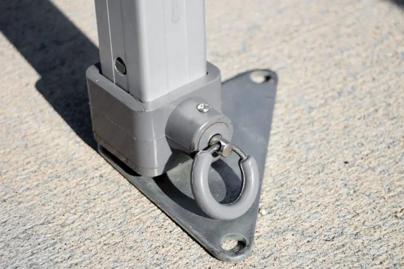 Close-up of a canopy tent leg secured with a rhino base plate and ring anchor on concrete Close-up of a canopy tent leg secured with a rhino base plate and ring anchor on concrete