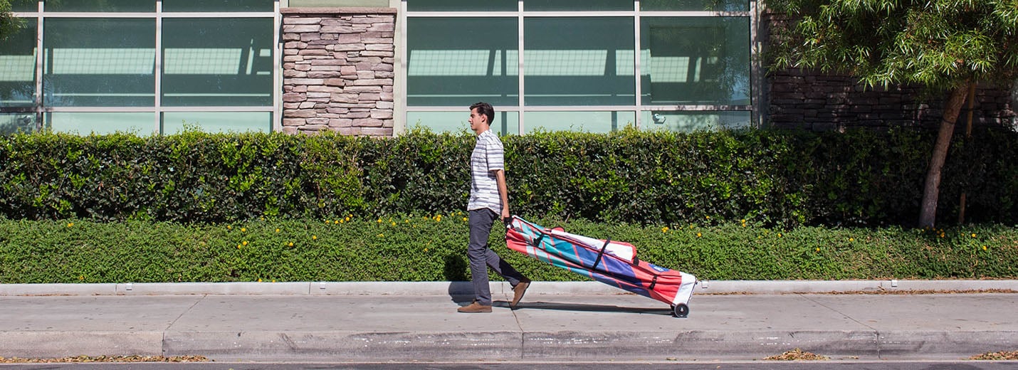 Custom canopy roller bag with wheels being pulled for easy pop up tent transport.