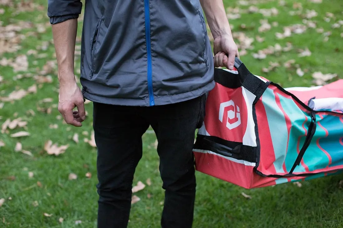 Close-up of a person carrying a custom printed canopy tent roller bag by the handle for transport