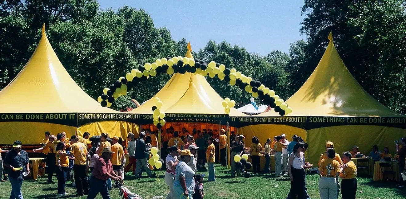 Yellow high peak event tents with balloon arch used for a large outdoor festival or sponsor area