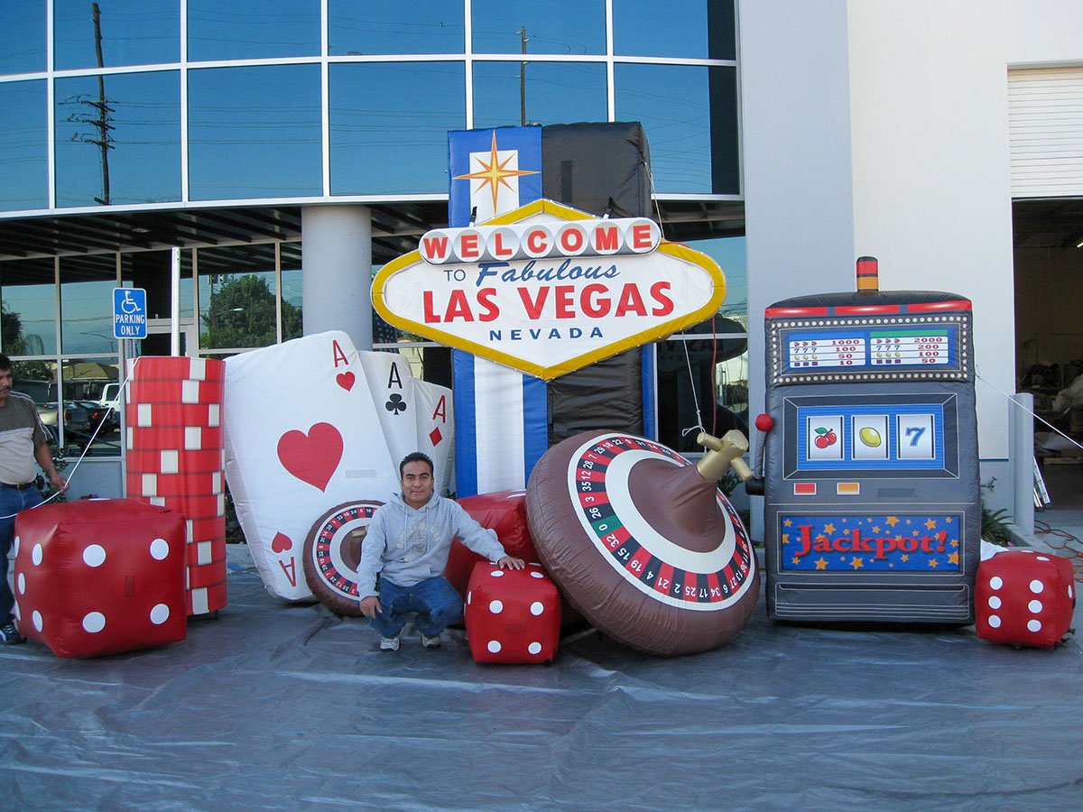 Custom inflatable Las Vegas sign and casino props including dice, cards, roulette wheel, and slot machine for themed events.